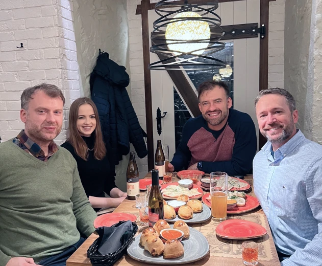 Men and girl smiling at the camera while sitting at the table